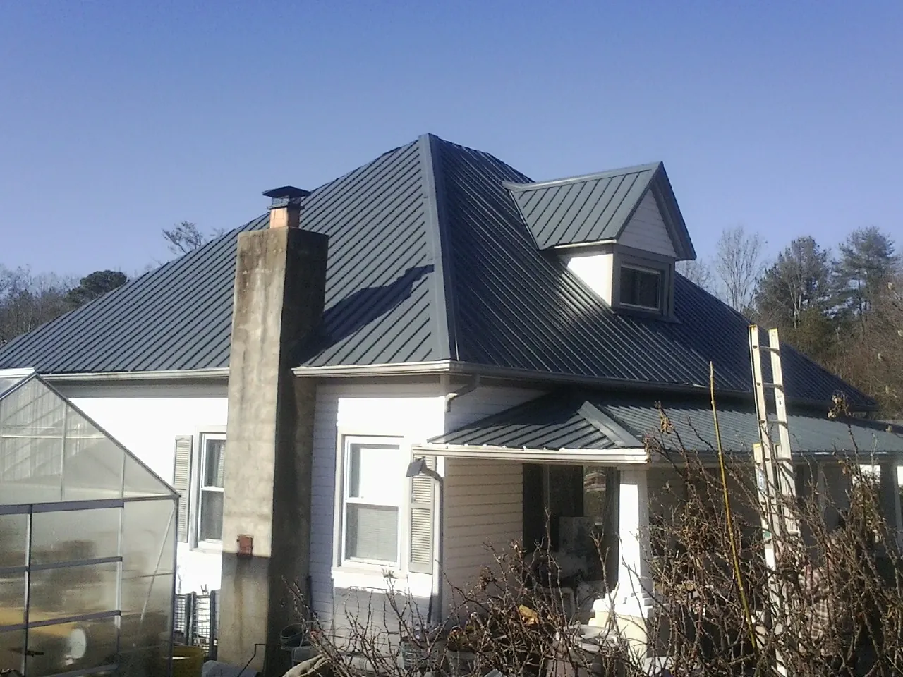 Dark blue standing seam metal roof on a white farmhouse with dormer — Slate & Tile Roof Repair by Roofing Brothers in Deckerville
