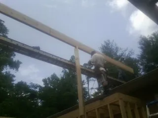 Carpenter setting a ridge beam over a new addition frame — Ice Dam Removal by Roofing Brothers in Deckerville