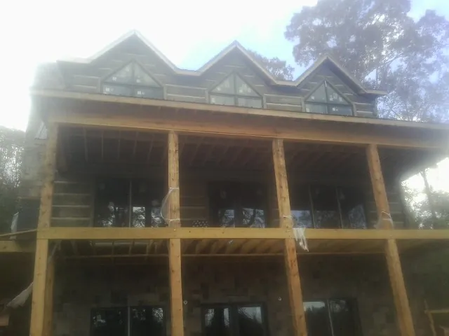 Dormers and porch framing on a large log home under construction — Roof Coating work by our crew in Deckerville